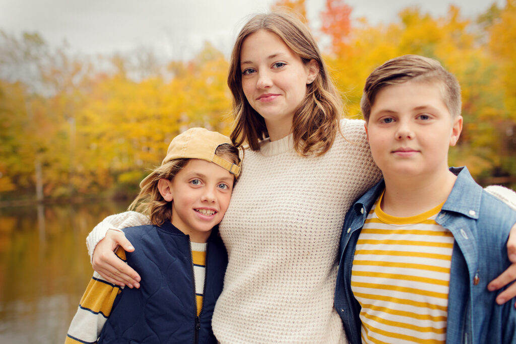 Siblings smiling at the camera in fall colors for an outdoor fall mini session in Carthage, Indiana.