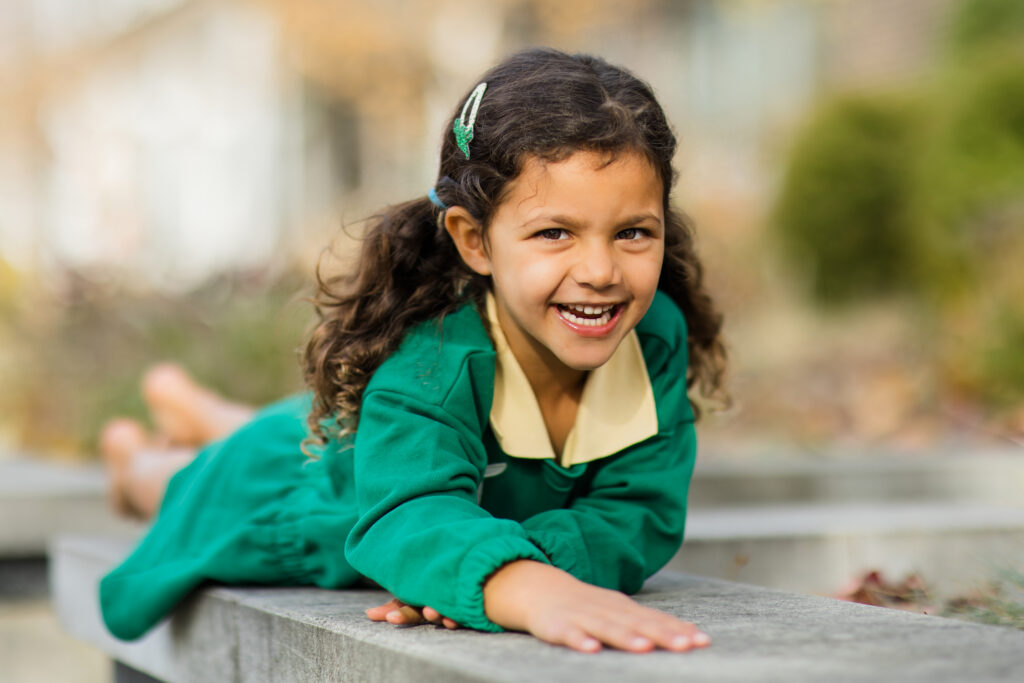Girl in green dress laughing and looking straight at the camera.