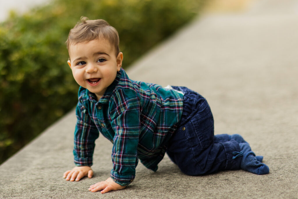 Toddler in flannel shirt and jeans crawling outside.