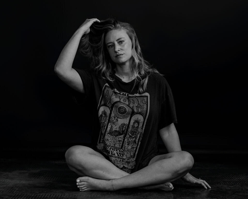Woman sitting on the floor and touching her hair in a t-shirt.